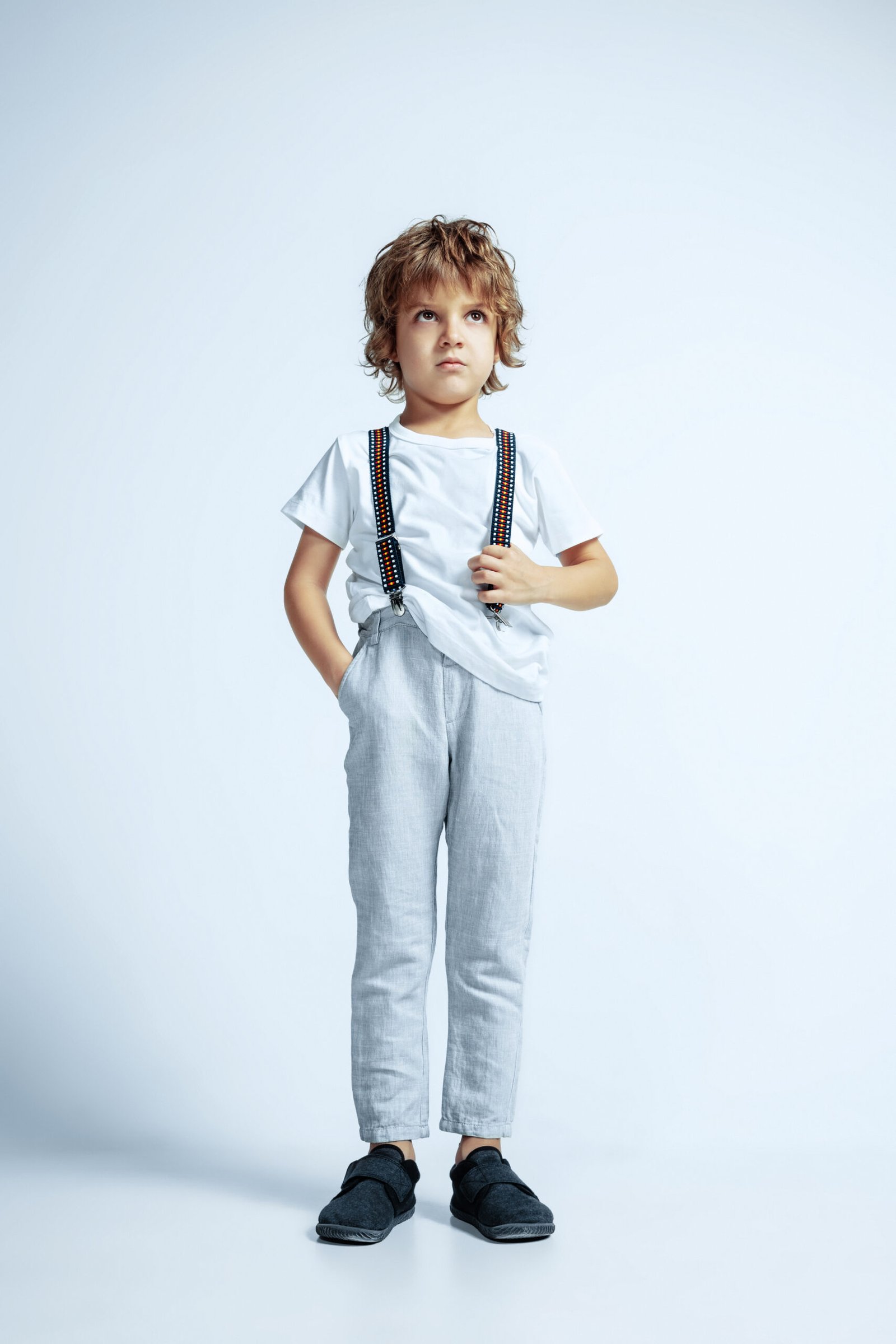 Pretty young boy in casual clothes on white studio background